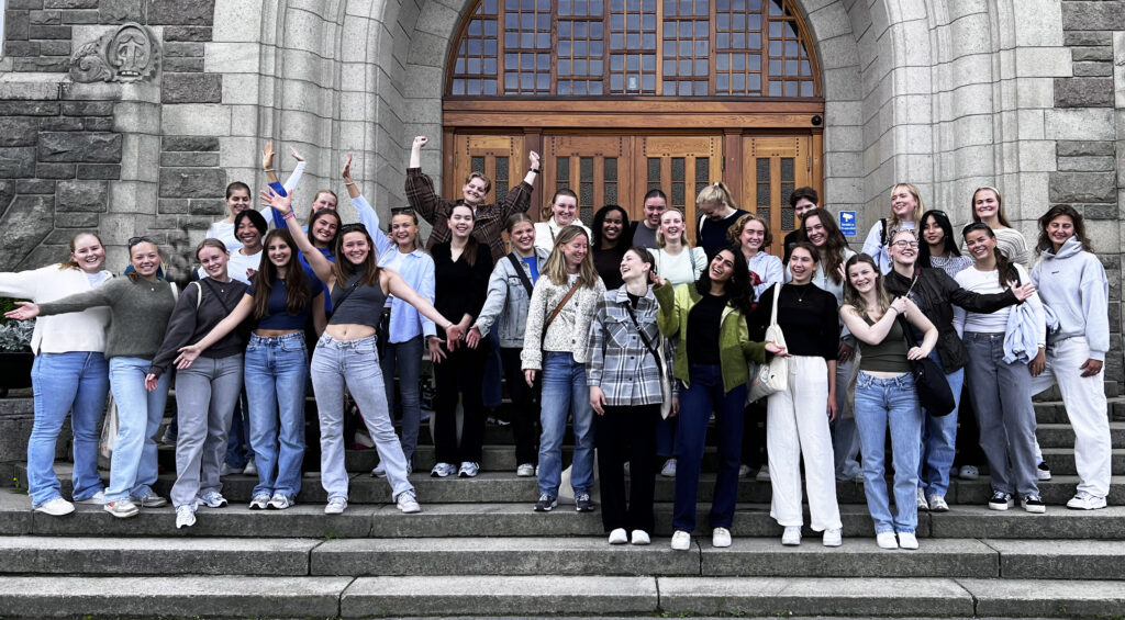 Mange kvinnelige studenter er samlet i trappen foran hovedbygningen på Gløshaugen