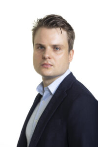 portrett av en mann med blå skjorte og dressjakke