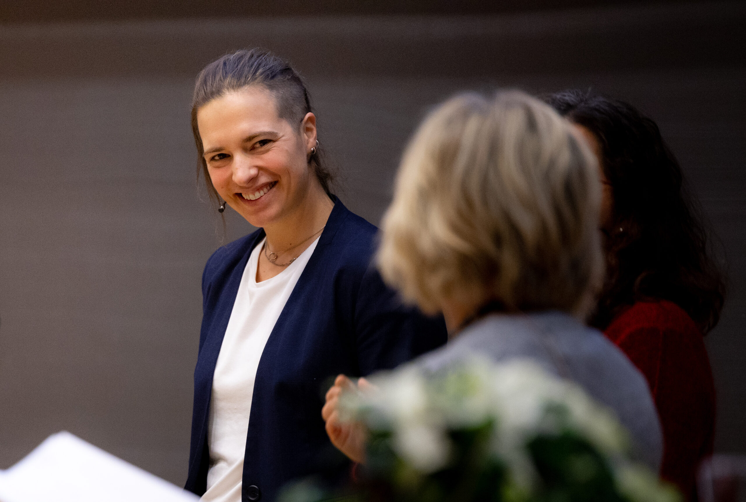 Inga Strümke smiler og ser bort på en person som står mellom henne og kamera.